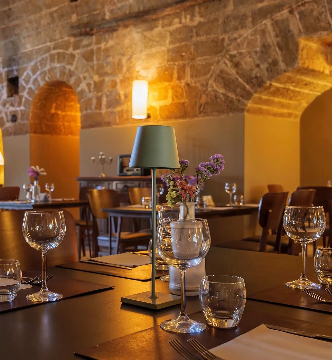 A candlelit table set for dinner in the stone-vaulted dining room