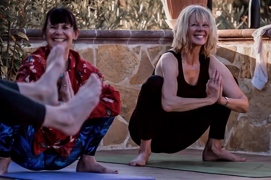 Two smiling women in a yoga pose on a retreat