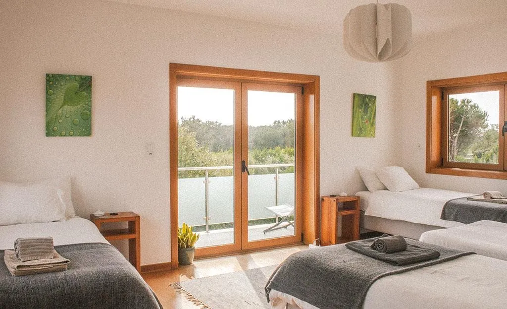 A twin bedroom with a balcony at the Sintra retreat house